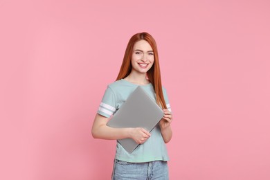 Photo of Smiling young woman with laptop on pink background