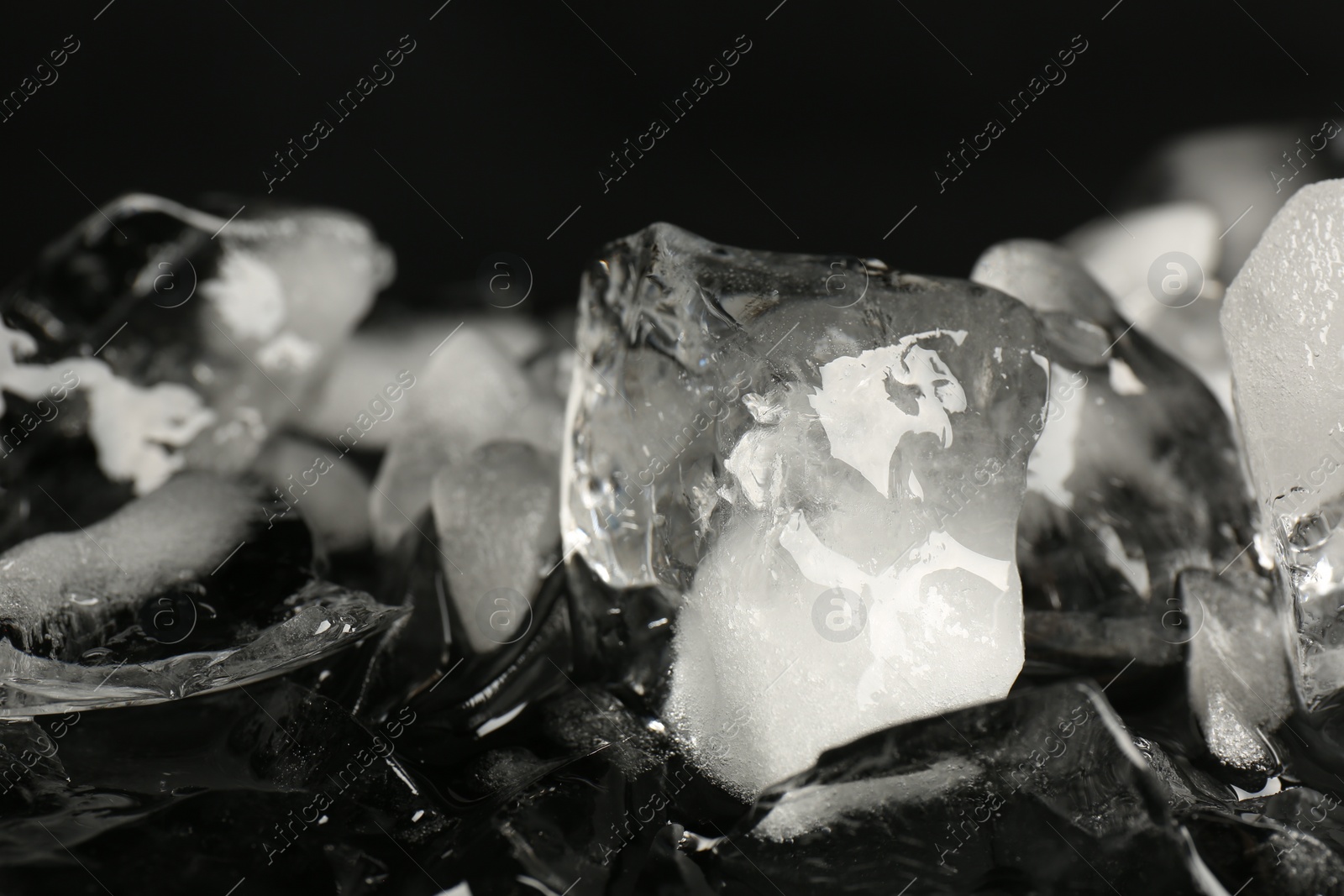 Photo of Pile of crushed ice on black mirror surface, closeup