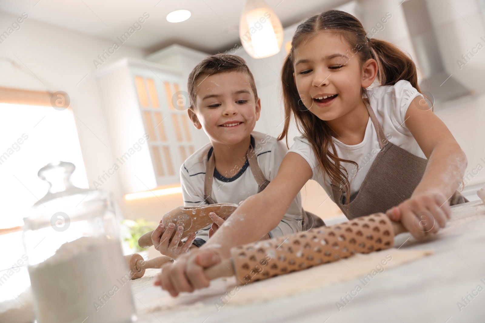 Photo of Cute little children cooking dough together in kitchen