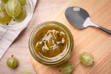 Photo of Jar of delicious gooseberry jam and fresh berries, flat lay