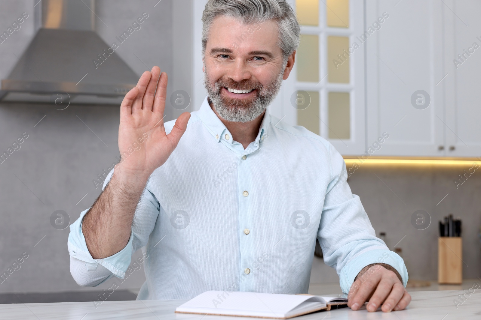 Photo of Man waving hello during video chat at home, view from webcam
