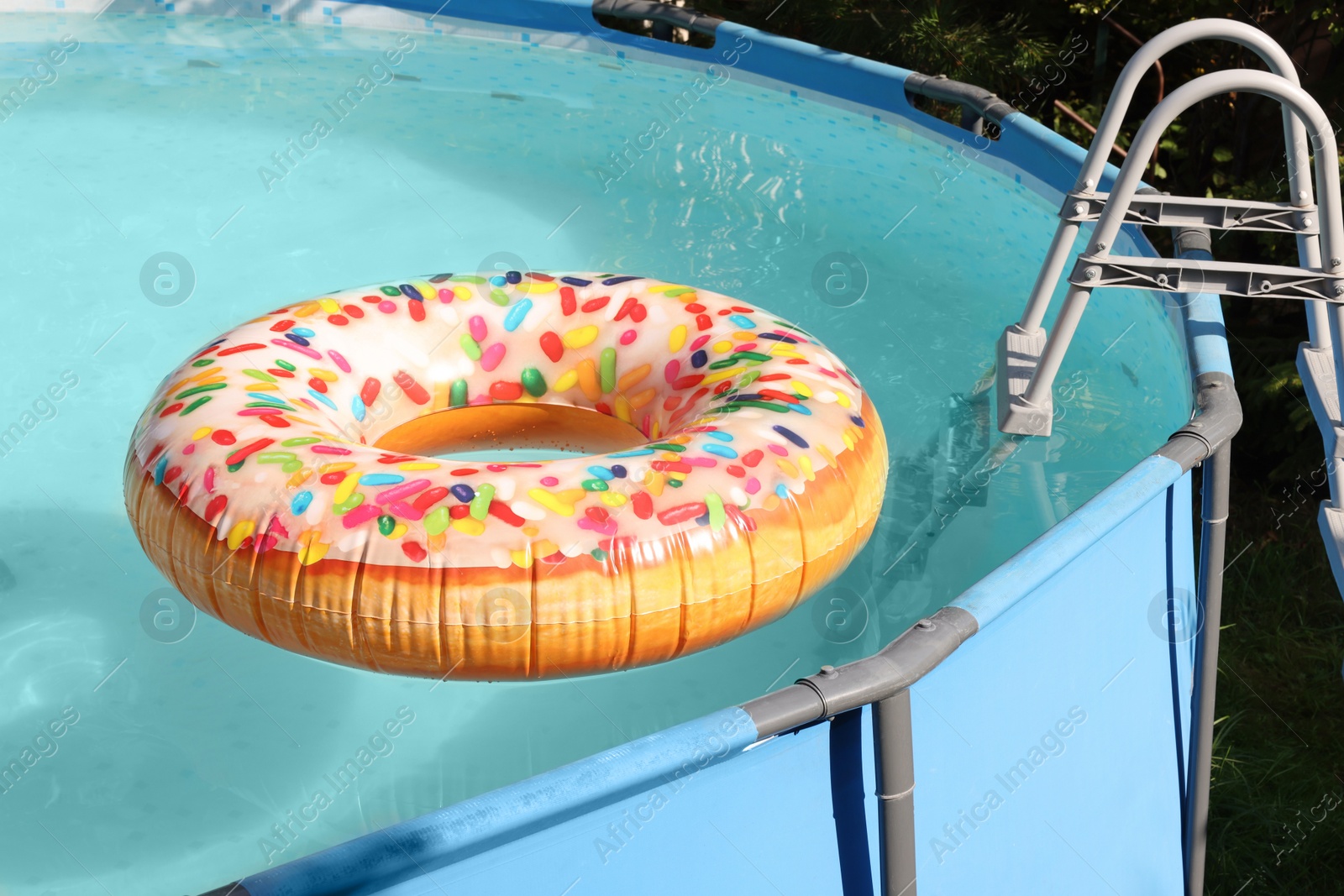 Photo of Inflatable ring floating on water in above ground swimming pool outdoors