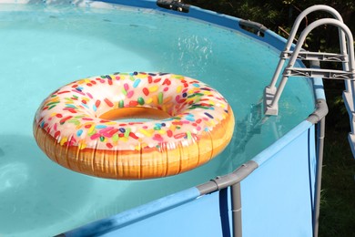 Photo of Inflatable ring floating on water in above ground swimming pool outdoors