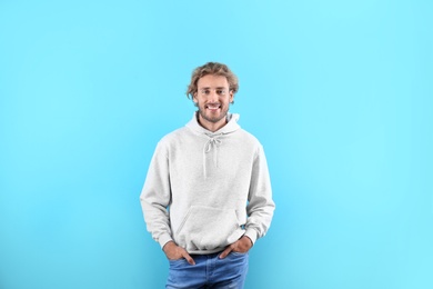 Portrait of man in hoodie sweater on color background. Space for design