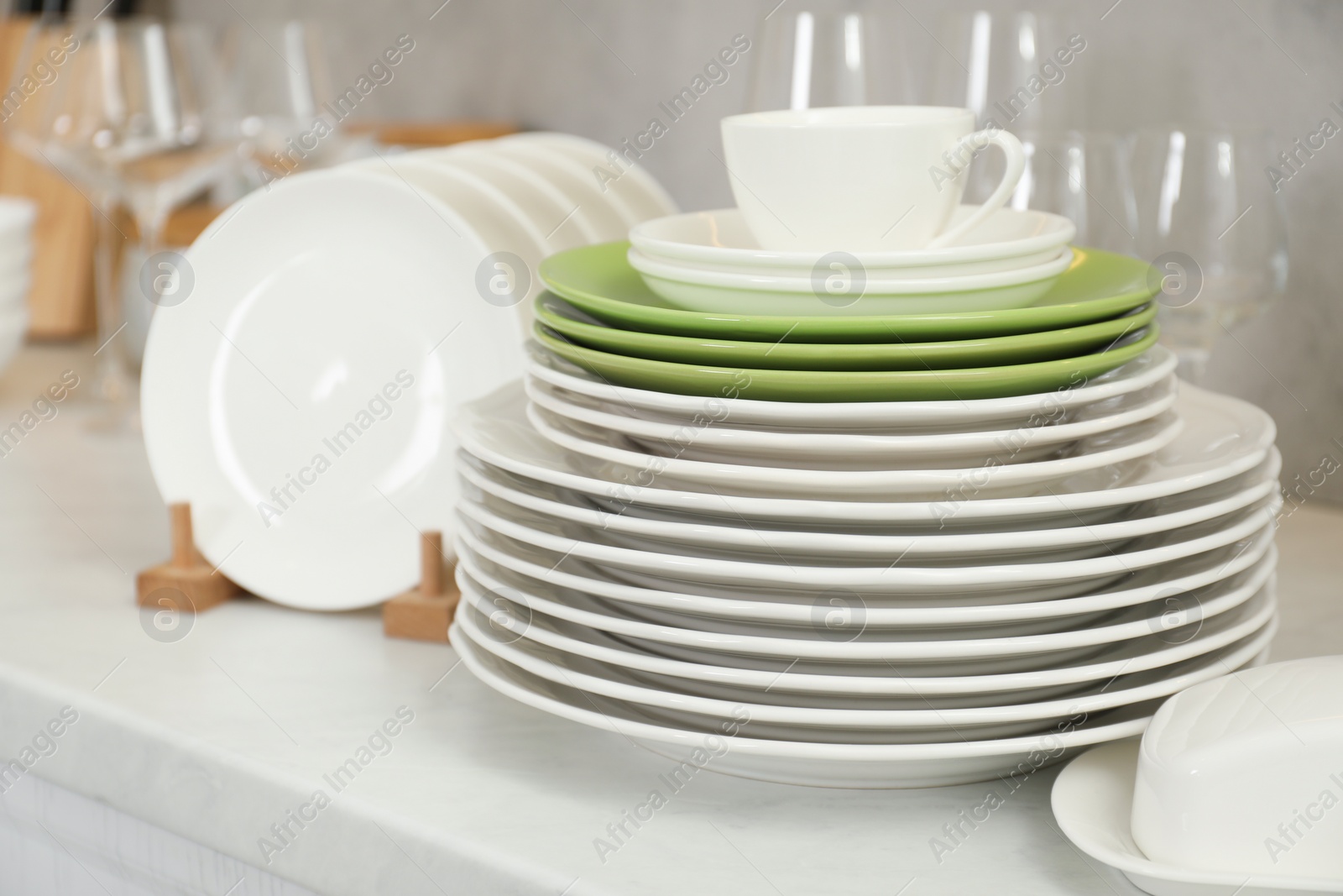 Photo of Clean plates, cup, glasses and butter dish on white countertop in kitchen
