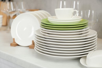 Clean plates, cup, glasses and butter dish on white countertop in kitchen