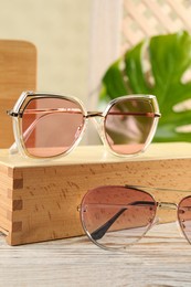 Photo of Stylish sunglasses on white wooden table. Summer accessories