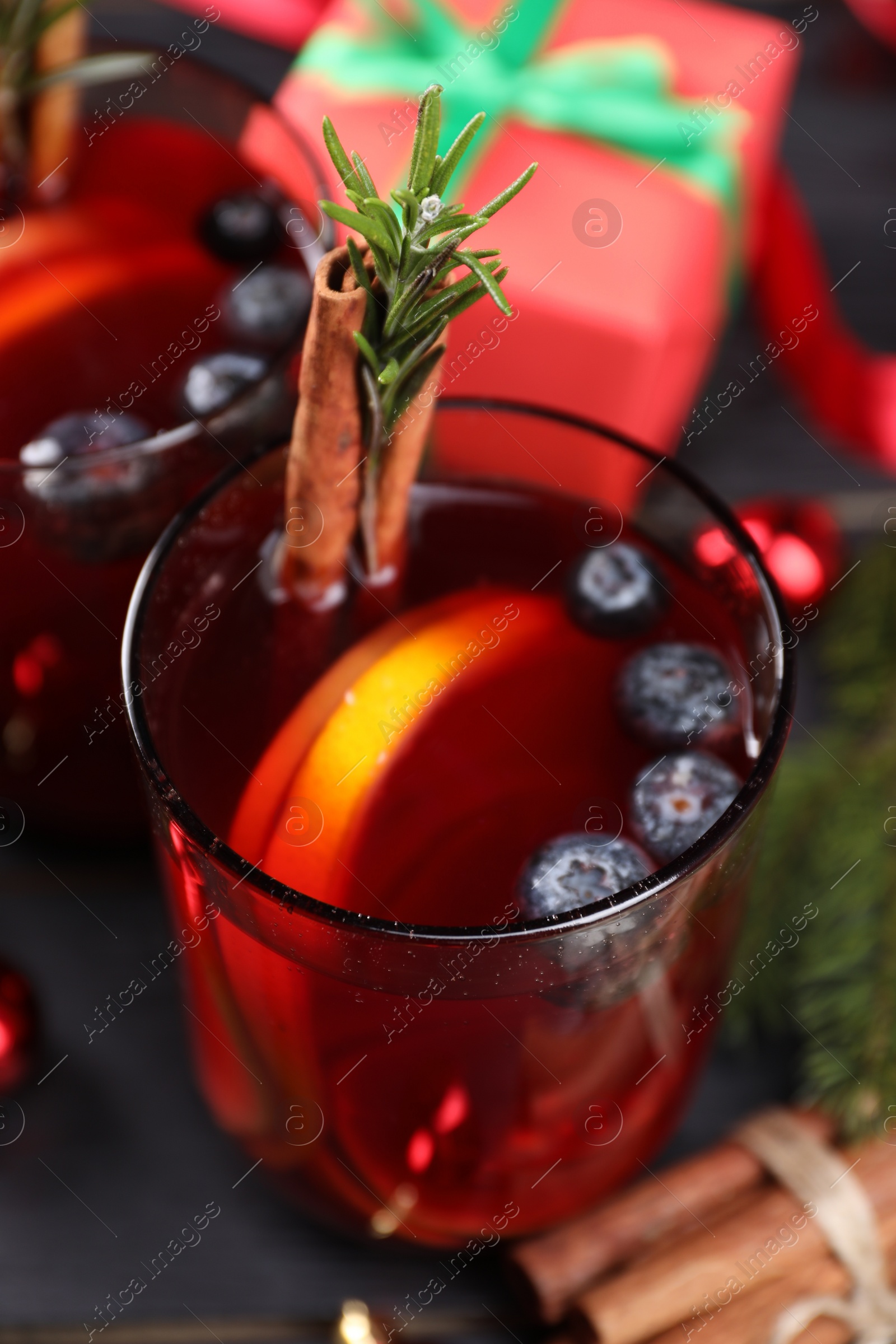 Photo of Aromatic Sangria drink in glasses, ingredients and Christmas decor on black wooden table