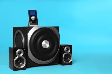 Photo of Modern powerful audio speaker system with remote on light blue background, space for text