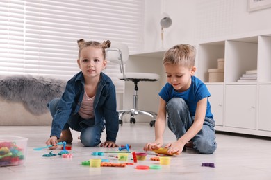 Photo of Cute little children playing on warm floor at home. Heating system