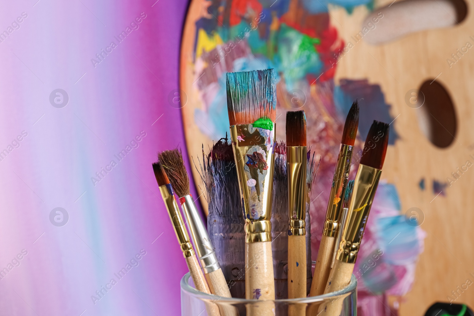 Photo of Brushes with colorful paints and wooden artist's palette. Space for text