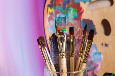 Photo of Brushes with colorful paints and wooden artist's palette. Space for text
