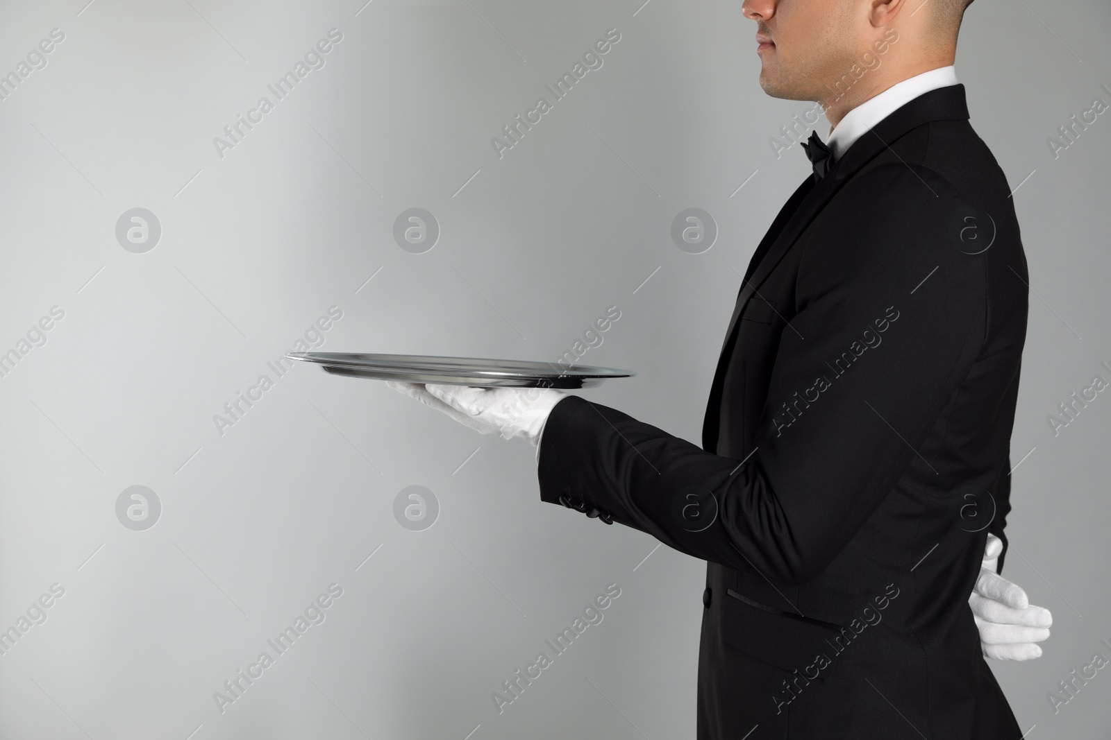 Photo of Butler with tray on light grey background, closeup. Space for text