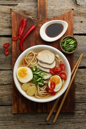 Photo of Delicious ramen in bowl served on wooden table, flat lay. Noodle soup