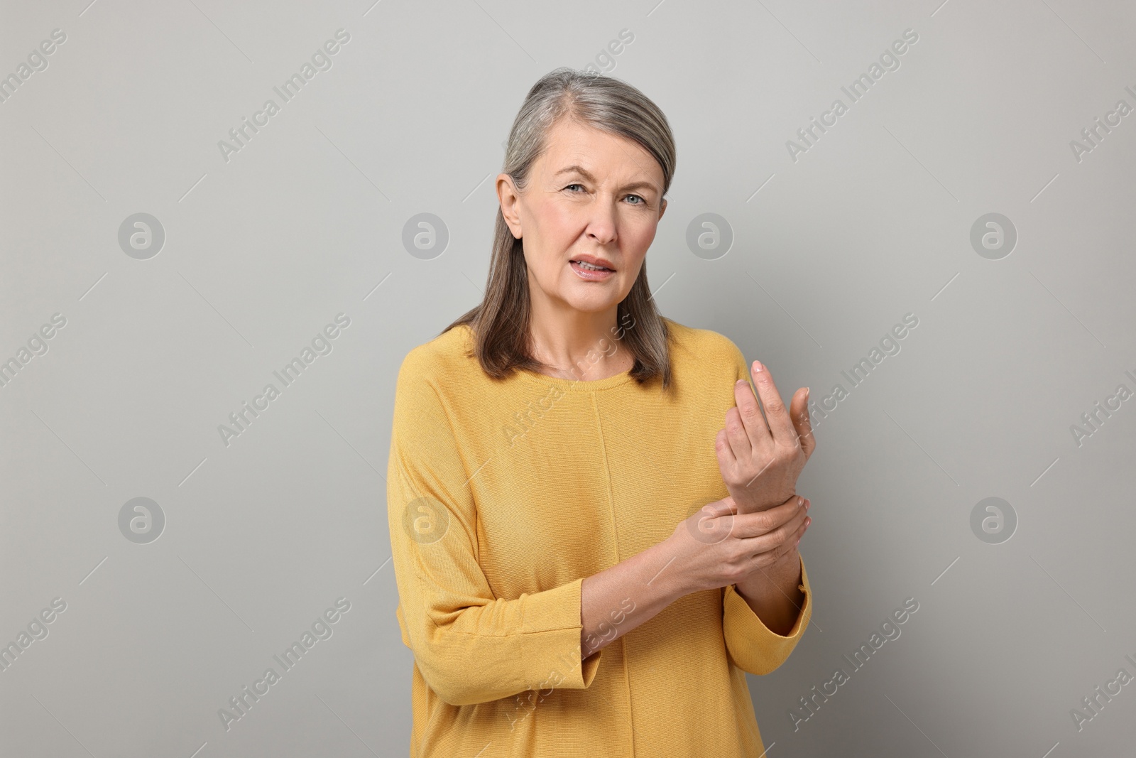 Photo of Arthritis symptoms. Woman suffering from pain in wrist on gray background