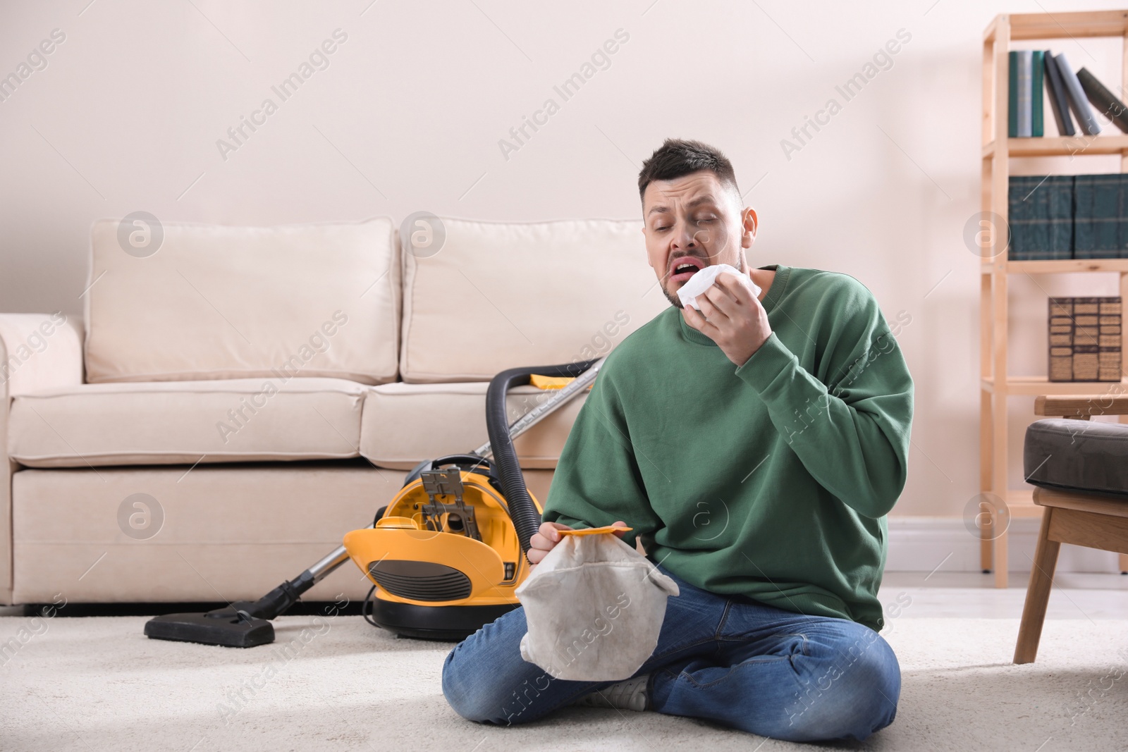 Photo of Man with vacuum cleaner bag suffering from dust allergy at home