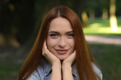 Photo of Portrait of beautiful young woman with red hair outdoors. Attractive lady looking into camera