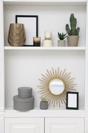 Beautiful houseplants and different decorative elements on shelving unit