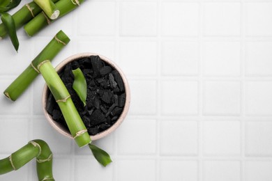 Fresh bamboo and charcoal on white tiled table, flat lay. Space for text