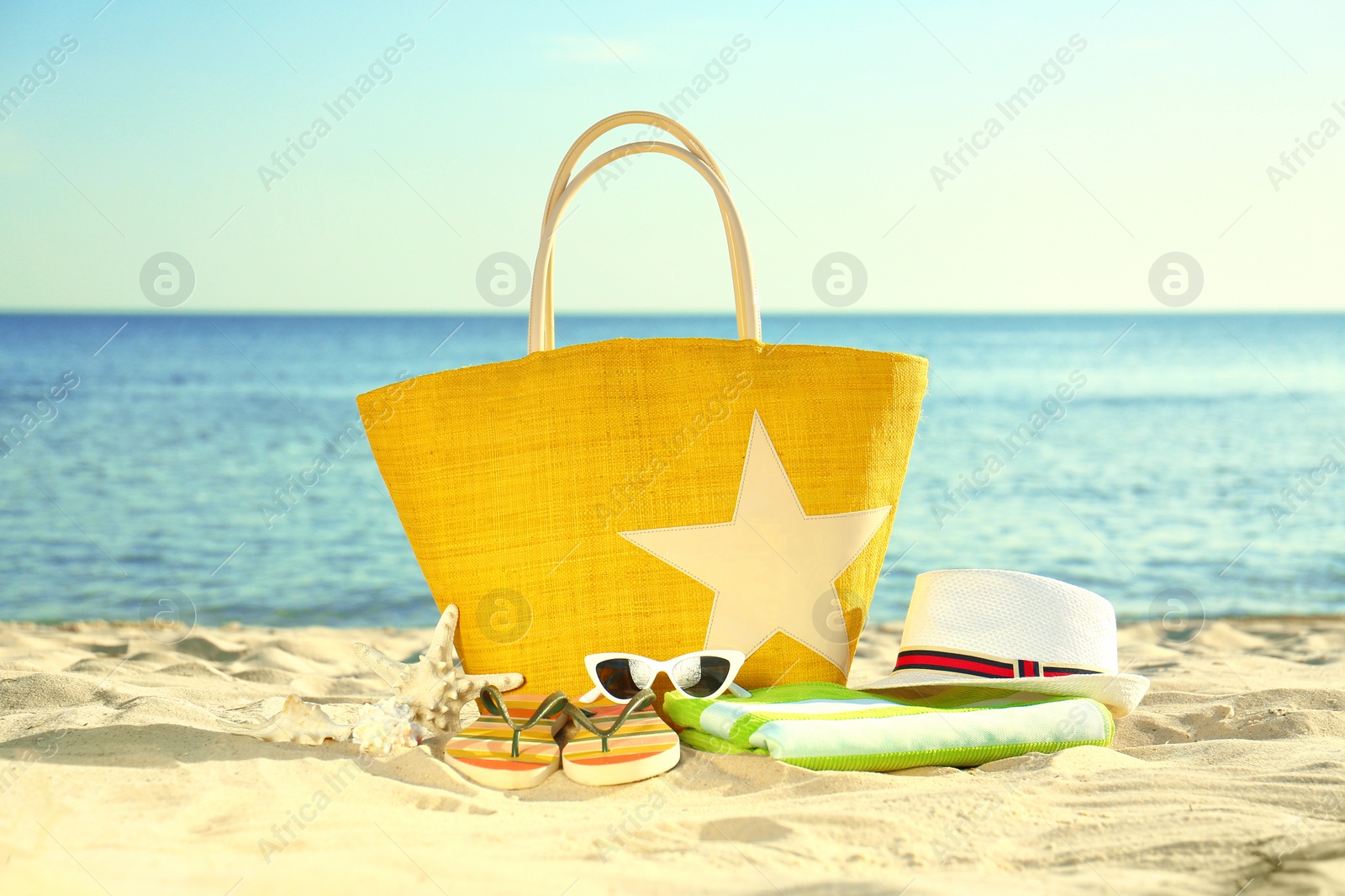 Photo of Composition with stylish beach accessories on sand near sea