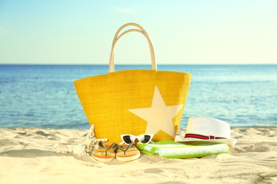 Composition with stylish beach accessories on sand near sea