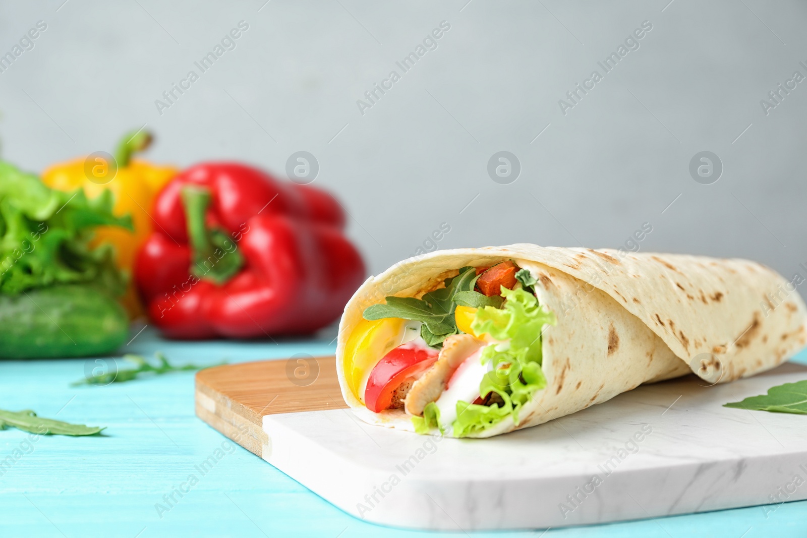 Photo of Delicious meat tortilla wrap on blue wooden table, space for text