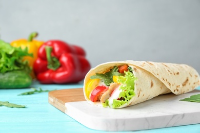 Delicious meat tortilla wrap on blue wooden table, space for text