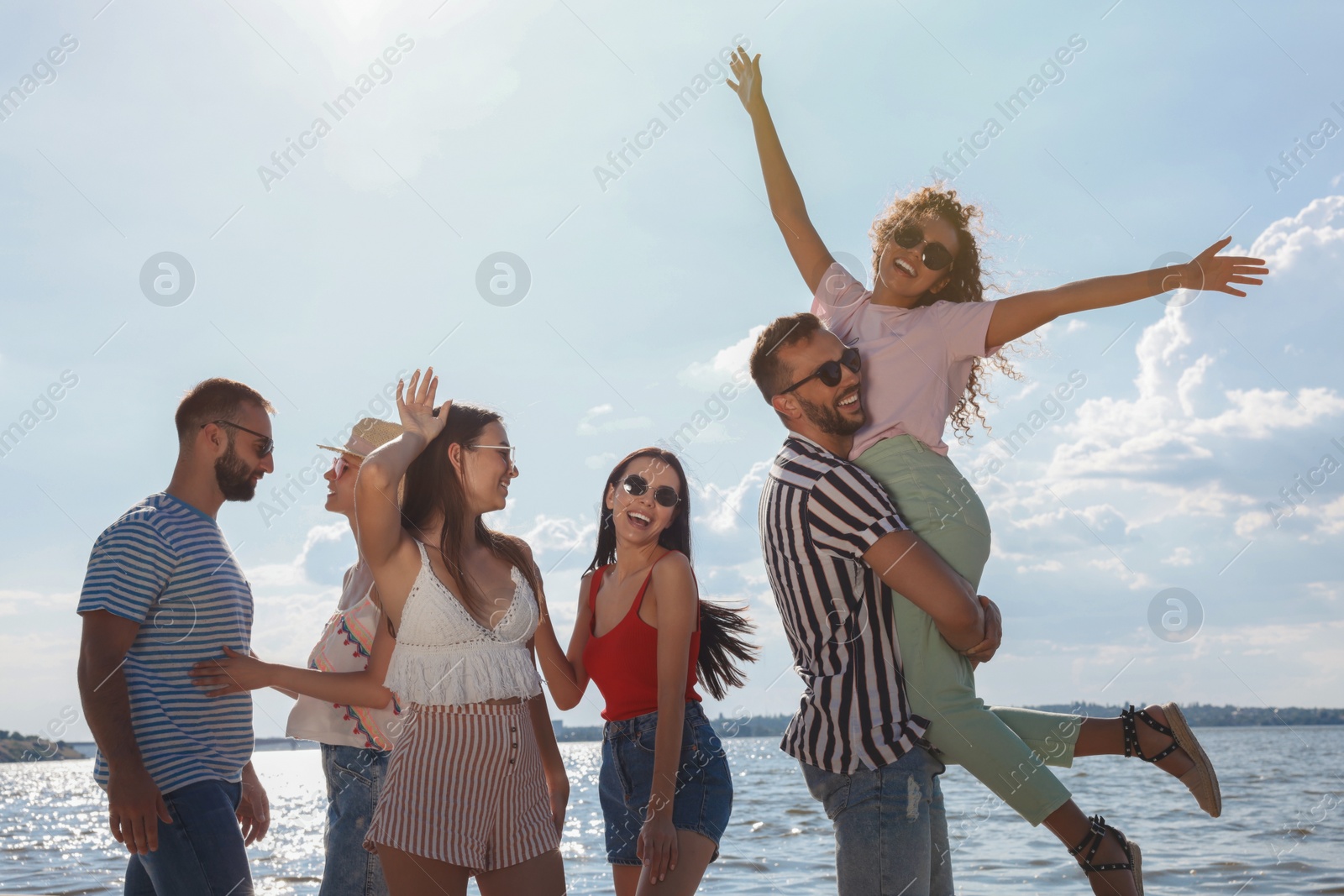 Photo of Group of friends having fun near river at summer party