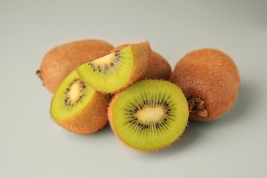 Photo of Heap of whole and cut fresh kiwis on white background, closeup