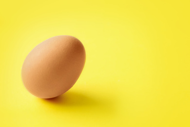 Photo of Raw chicken egg on yellow background. Space for text