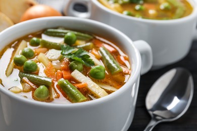 Photo of Bowl of tasty turnip soup and spoon on table, closeup