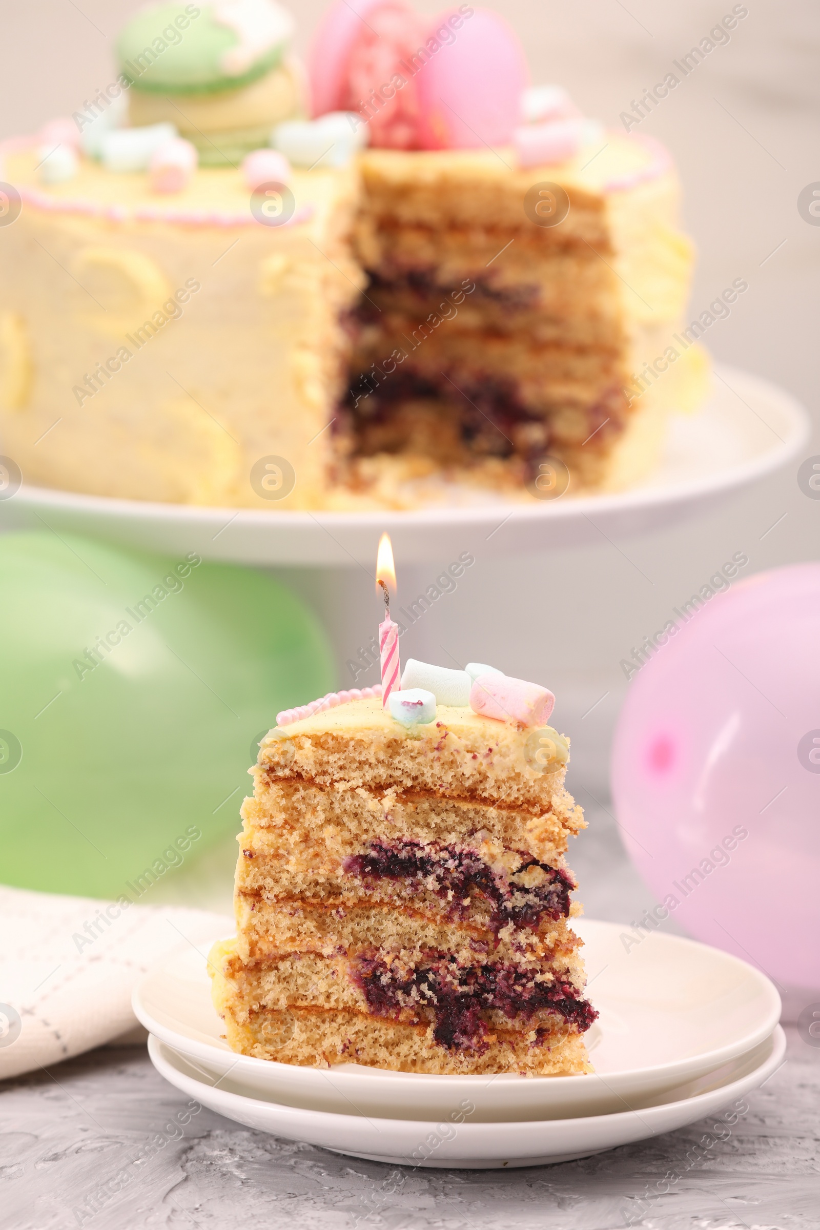 Photo of Piece of delicious cake with burning candle on light grey table
