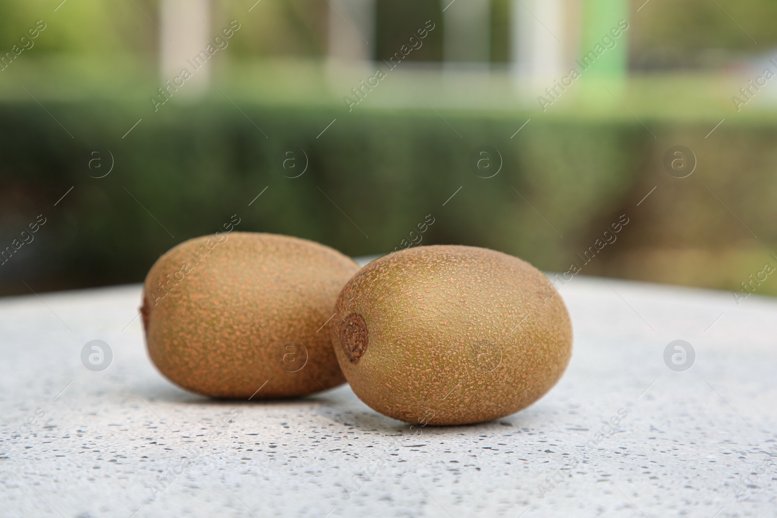 Photo of Whole fresh kiwis on white table with pattern outdoors