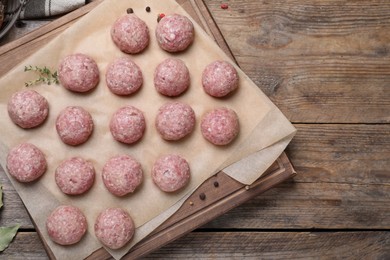 Photo of Many fresh raw meatballs on wooden table, flat lay Space for text