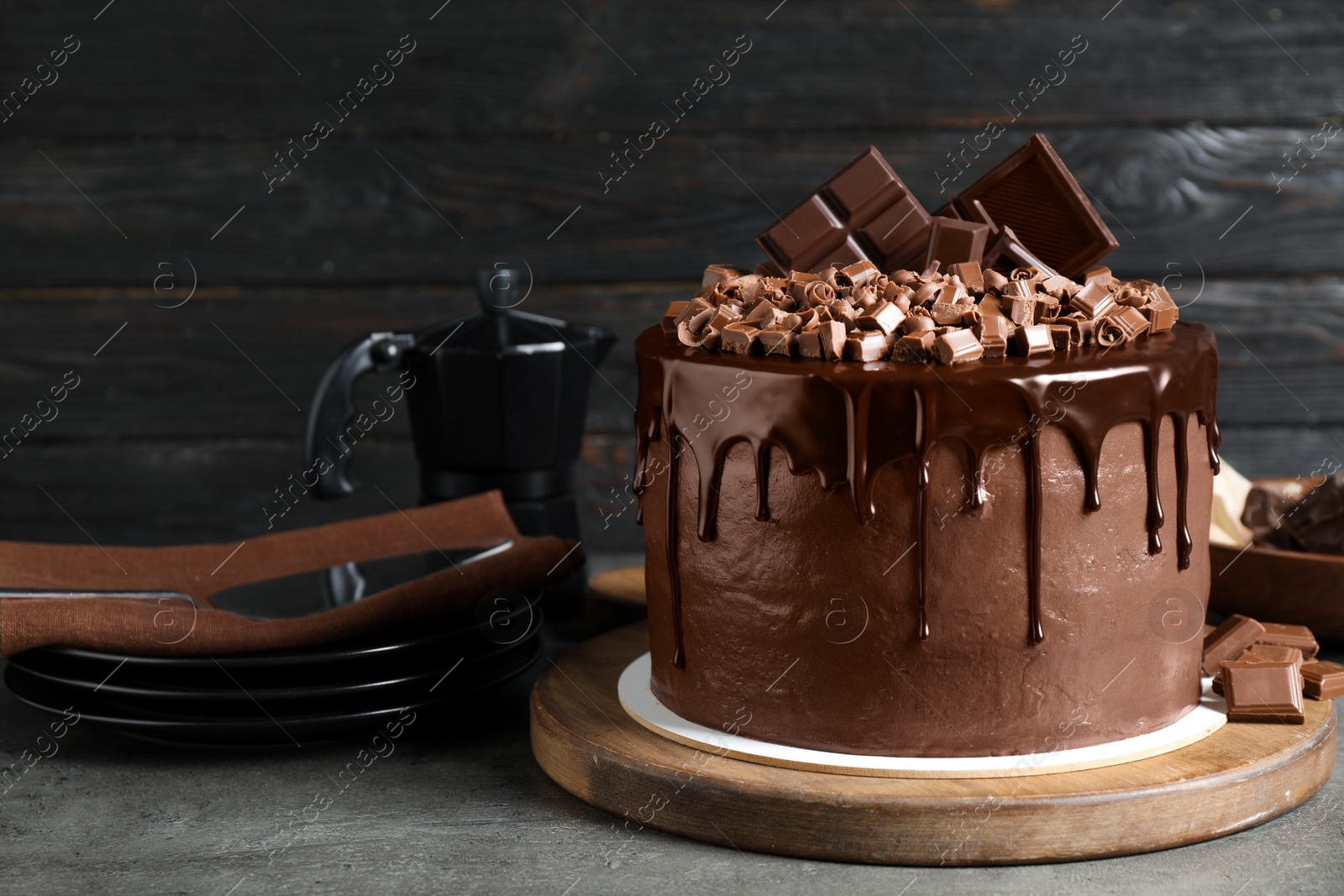 Photo of Freshly made delicious chocolate cake on grey table against black background