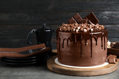 Photo of Freshly made delicious chocolate cake on grey table against black background