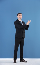 Photo of Business trainer applauding on color wall background