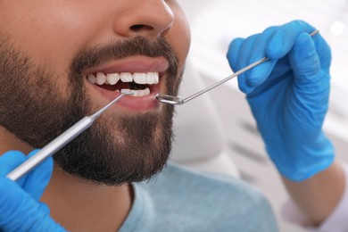 Photo of Dentist examining young man's teeth in clinic, closeup