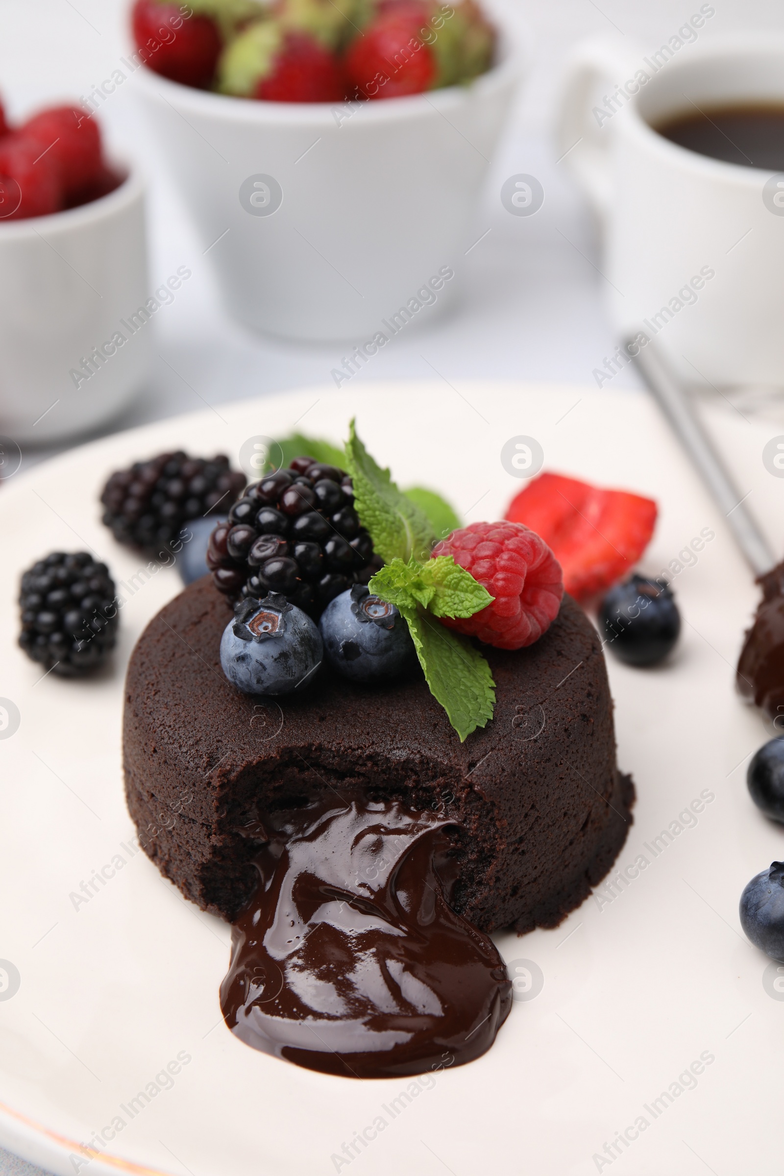 Photo of Delicious chocolate fondant, berries and mint on plate, closeup