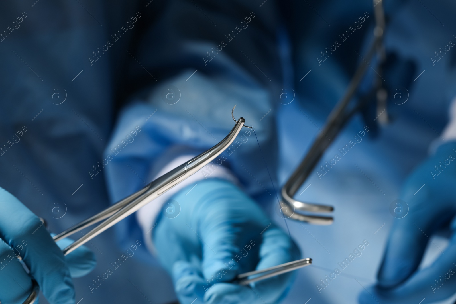 Photo of Professional surgeons with forceps and suture thread, closeup. Medical equipment