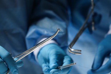 Photo of Professional surgeons with forceps and suture thread, closeup. Medical equipment