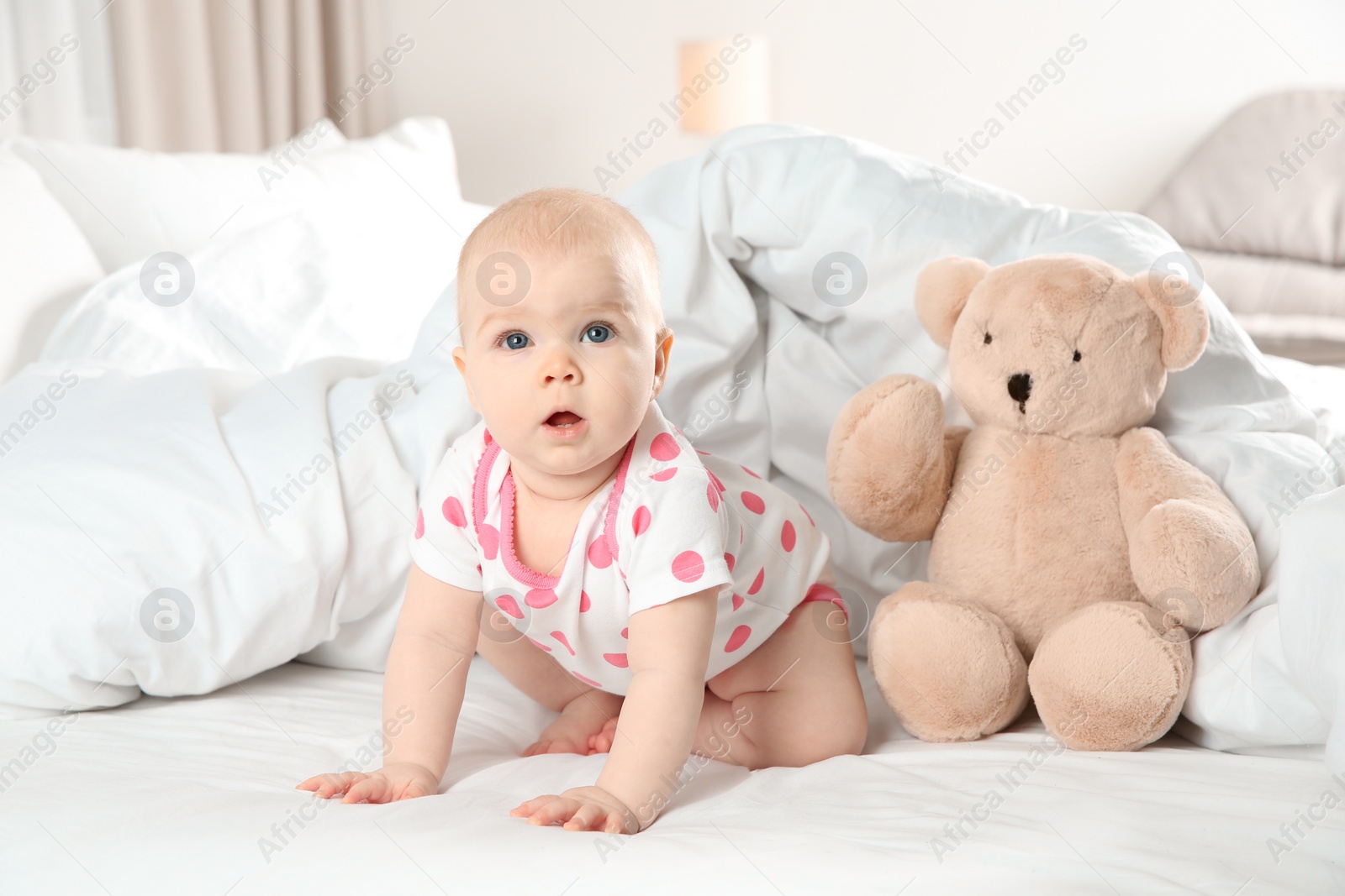 Photo of Cute baby girl with toy on bed at home. Bedtime schedule