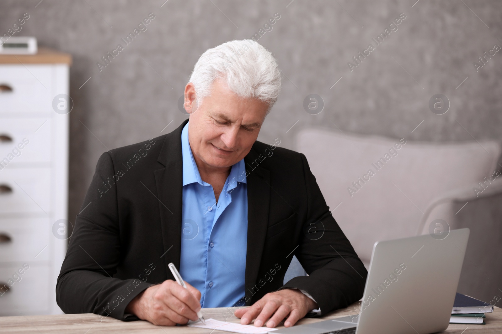 Photo of Portrait of senior man filling out lottery ticket at table