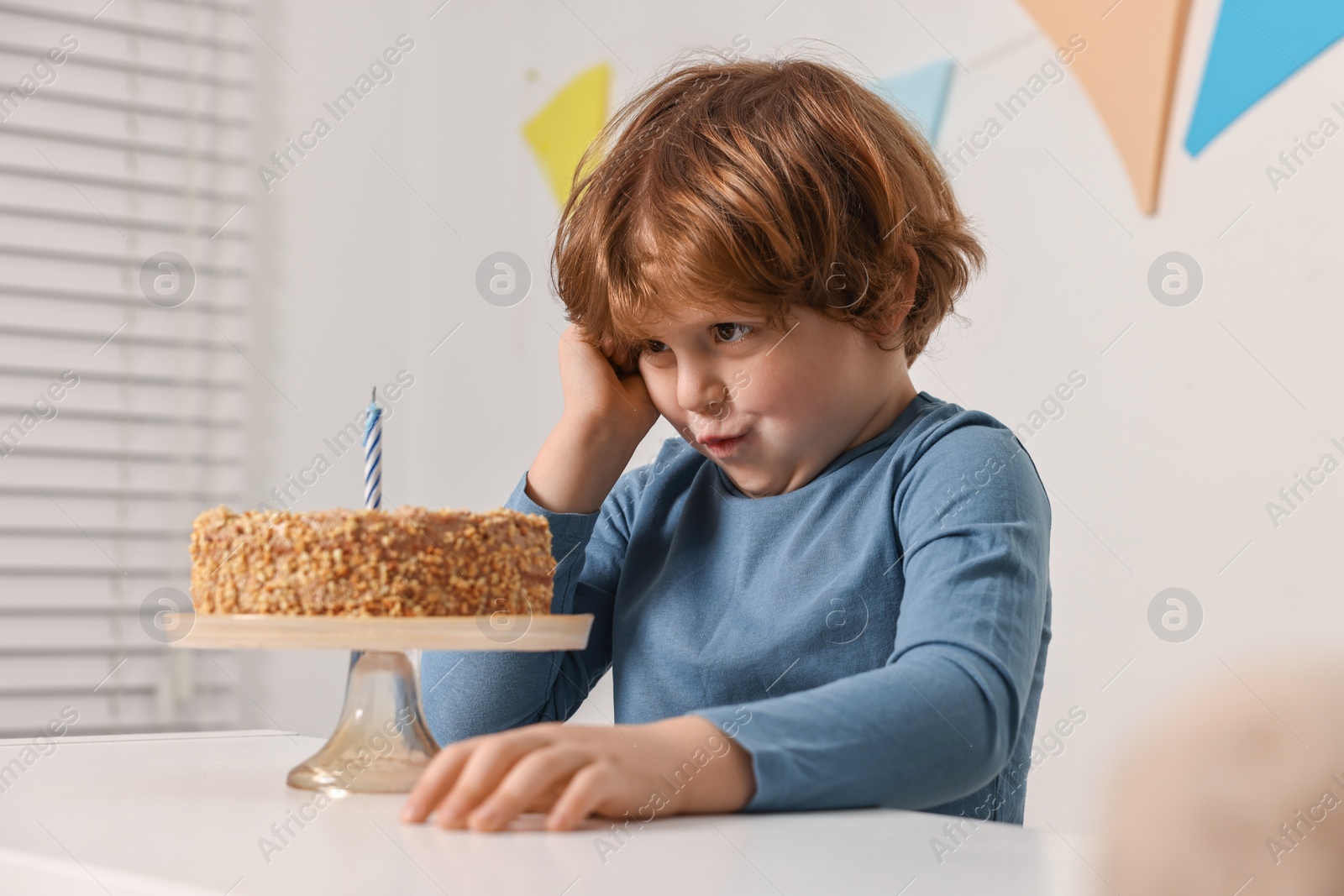 Photo of Cute boy with birthday cake at white table indoors