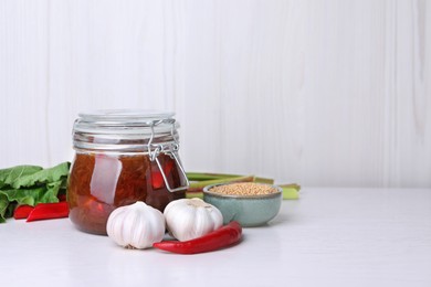 Tasty rhubarb sauce and ingredients on white table, space for text