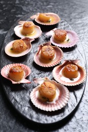 Delicious fried scallops in shells on black table, closeup