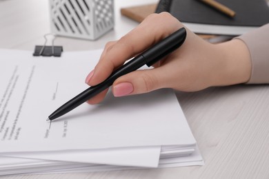 Photo of Woman signing document at wooden table, closeup