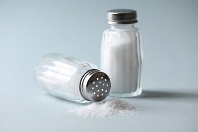 Photo of Natural salt in shakers on color background