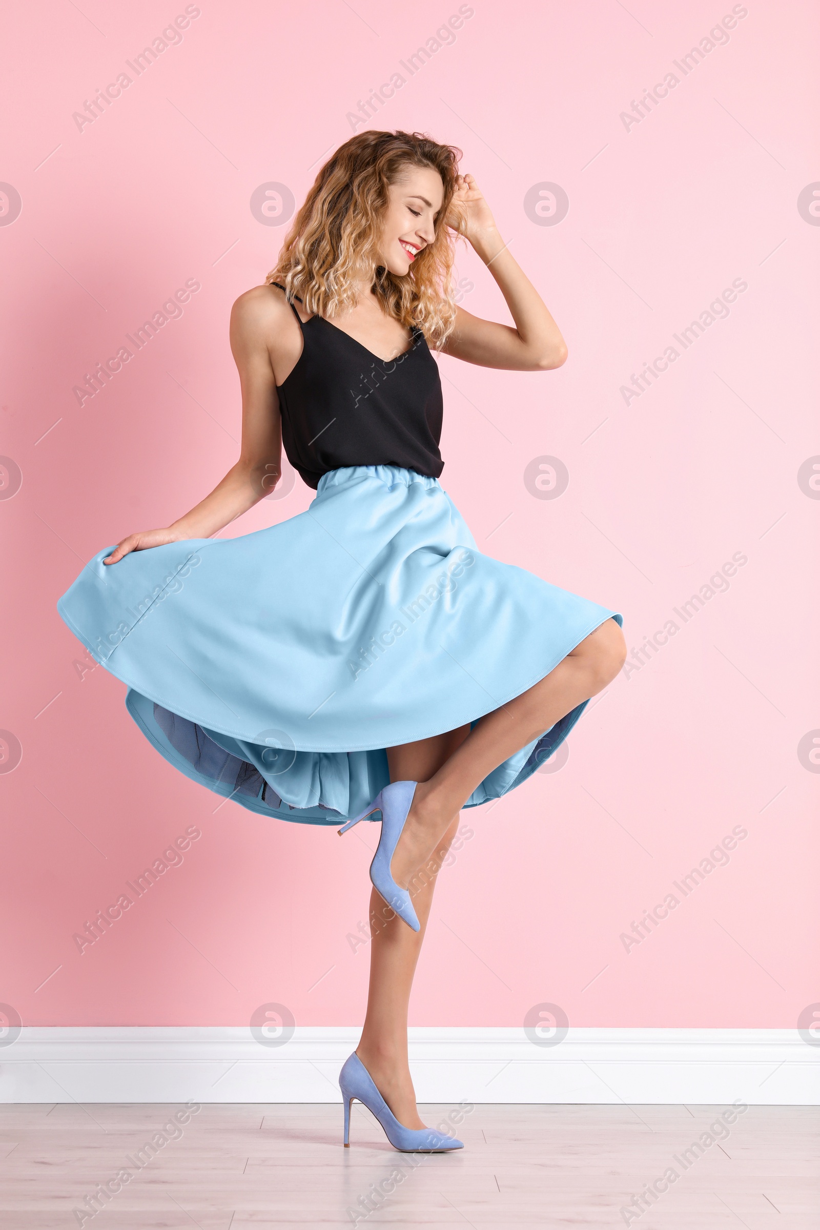 Photo of Young woman with beautiful long legs in stylish outfit near color wall