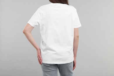 Photo of Woman in white t-shirt on grey background, back view